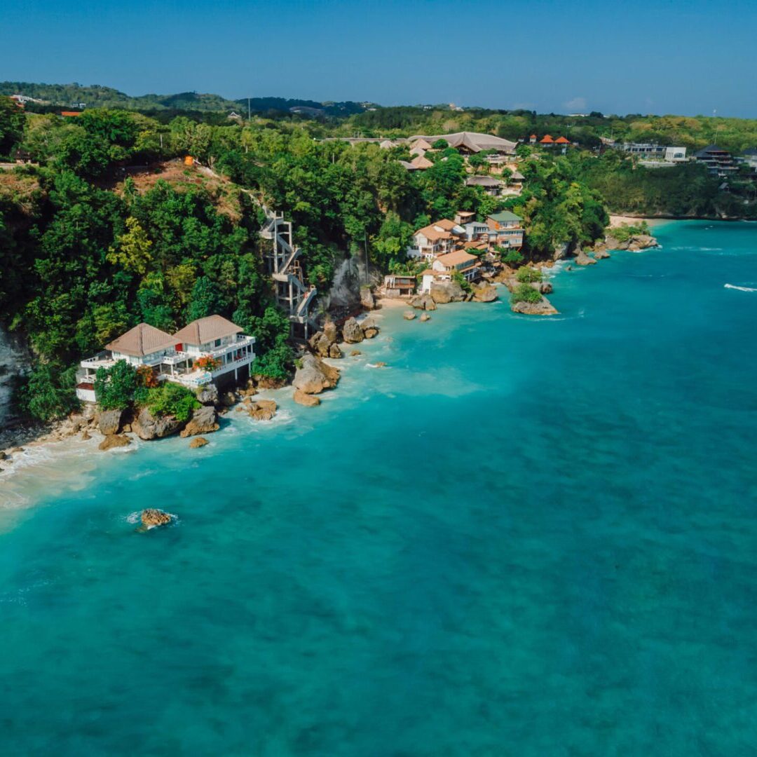 Aerial view of a tropical beach with turquoise waters and lush greenery.